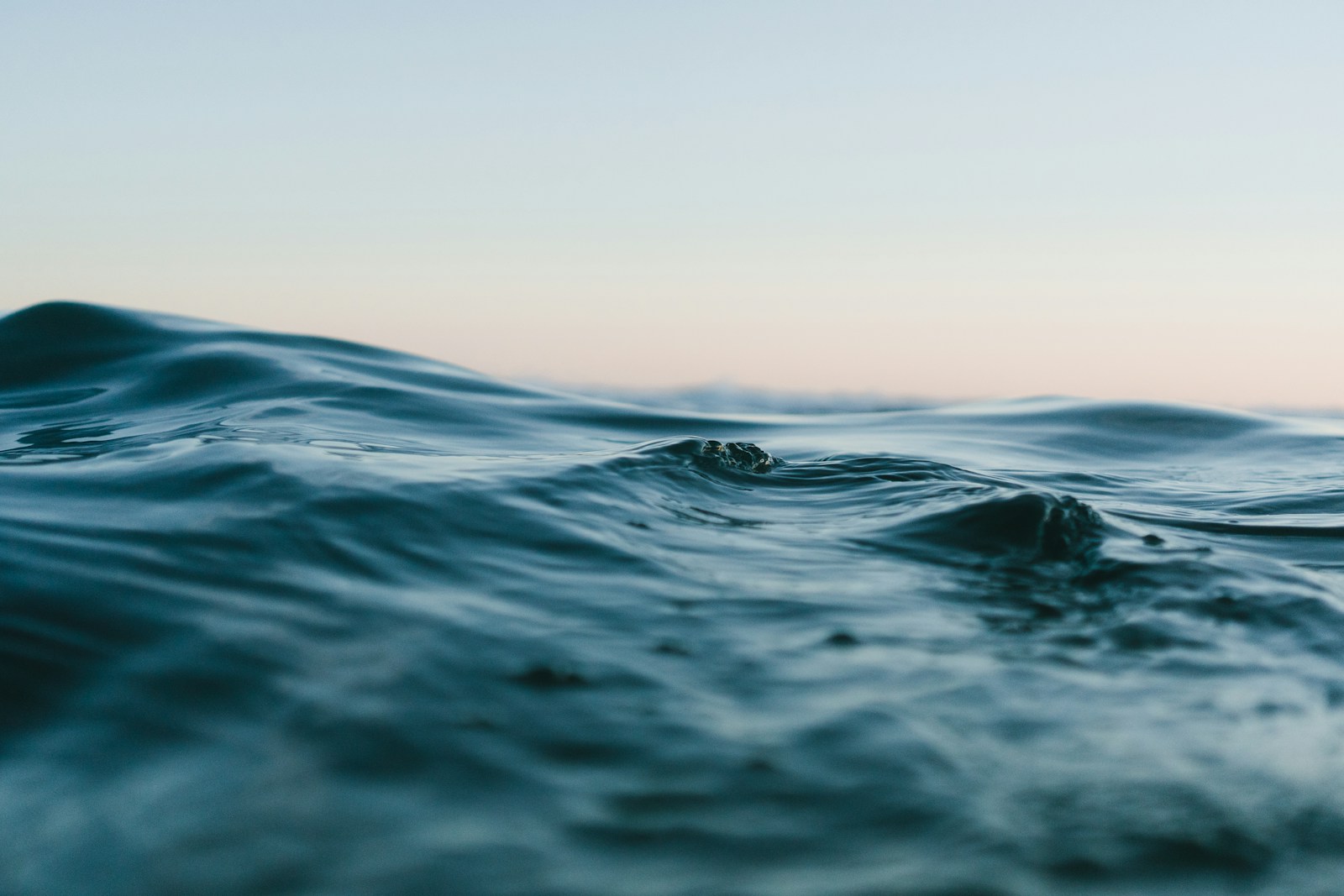 Gentle ocean waves beneath a wide, softly lit sky
