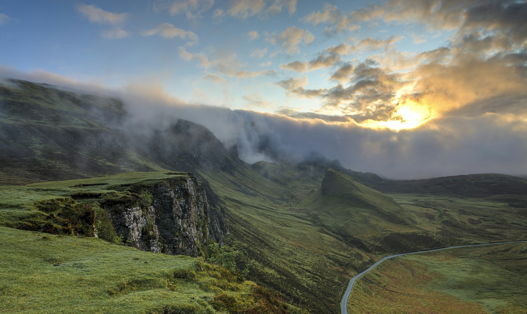 Soft morning light and mist settling over green hills